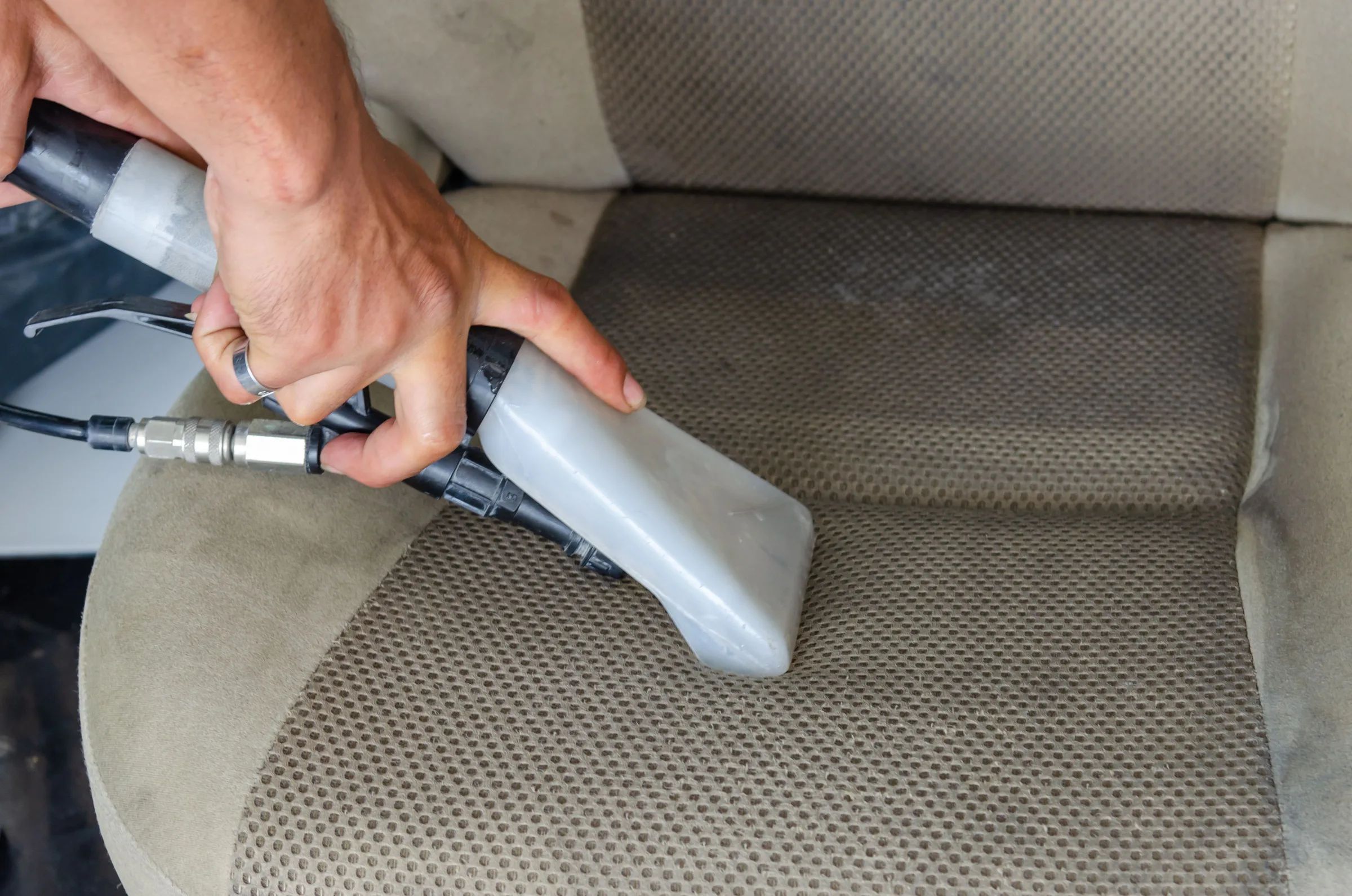 A hot-water extractor cleaning a cloth car seat